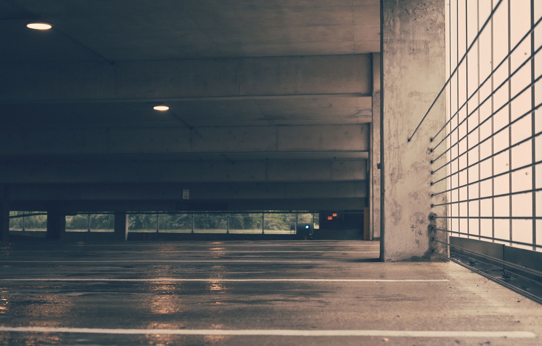 Deserted indoor parking garage with industrial design and wet concrete floor creating a moody ambiance.